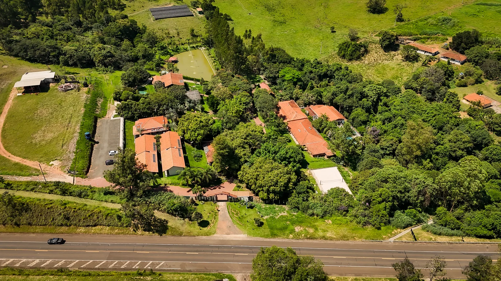 Vista aérea do Água Santa: telhados entre as copas das árvores, lago e mata em Descalvado