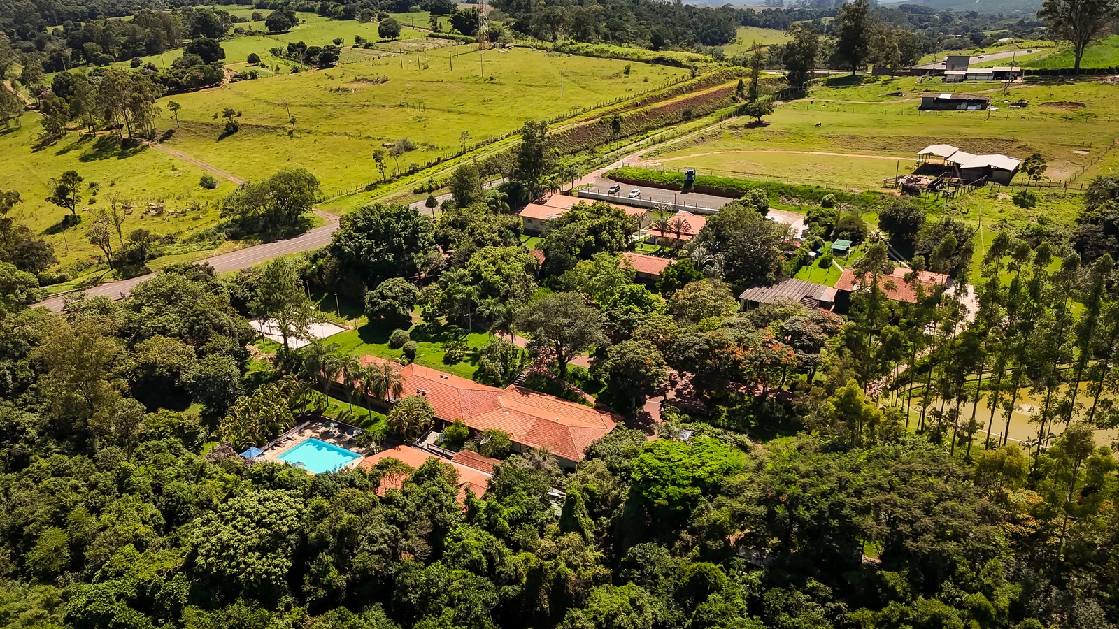 Vista aérea da piscina externa e dos chalés do Água Santa, cercados de mata