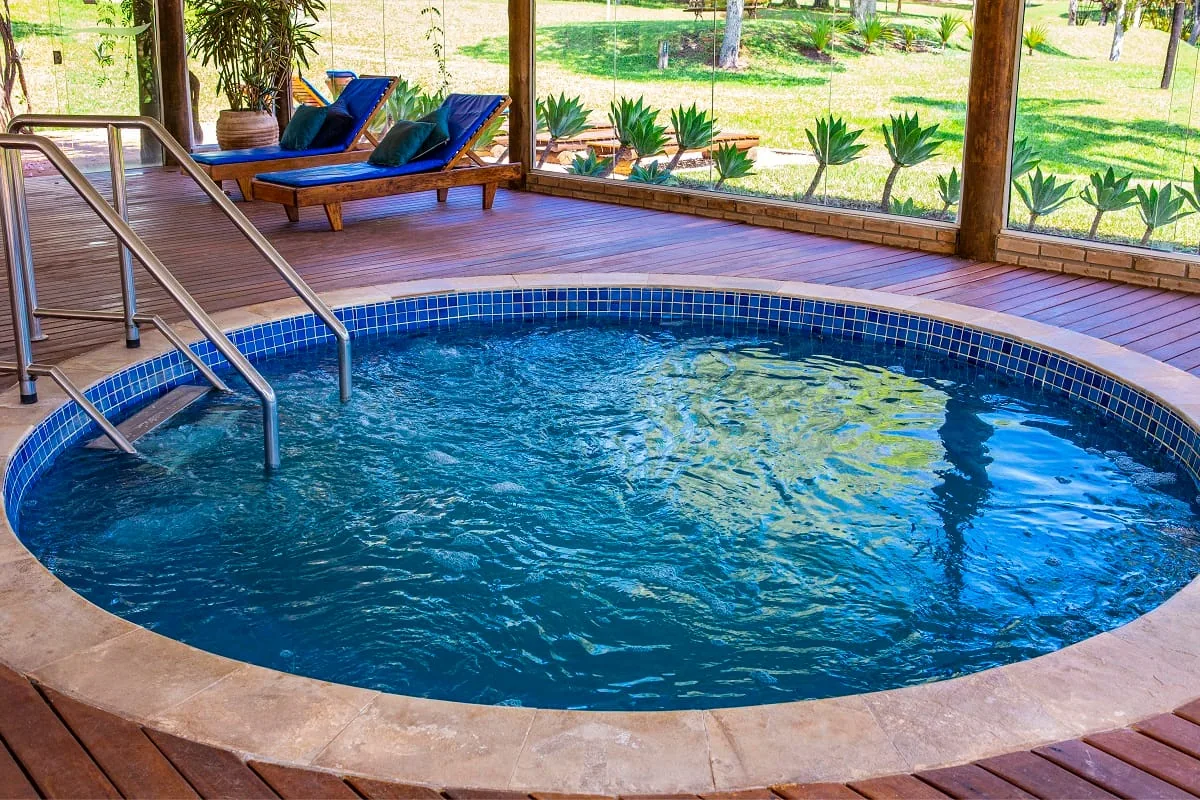 Piscina aquecida coberta, redonda, com deck de madeira e espreguiçadeiras