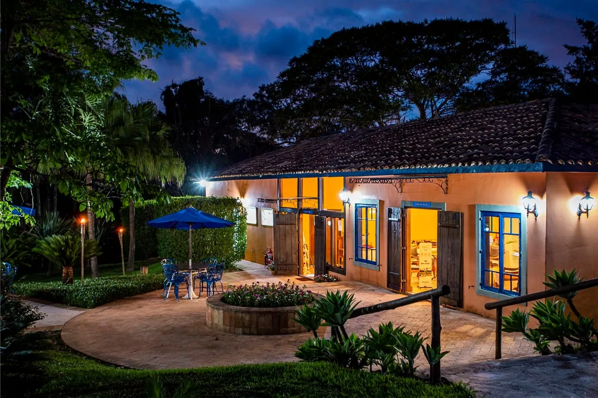 Fachada do casarão iluminada ao entardecer, com janelas azuis acesas