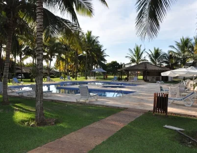 Piscina externa vista do gramado, com quiosque ao fundo