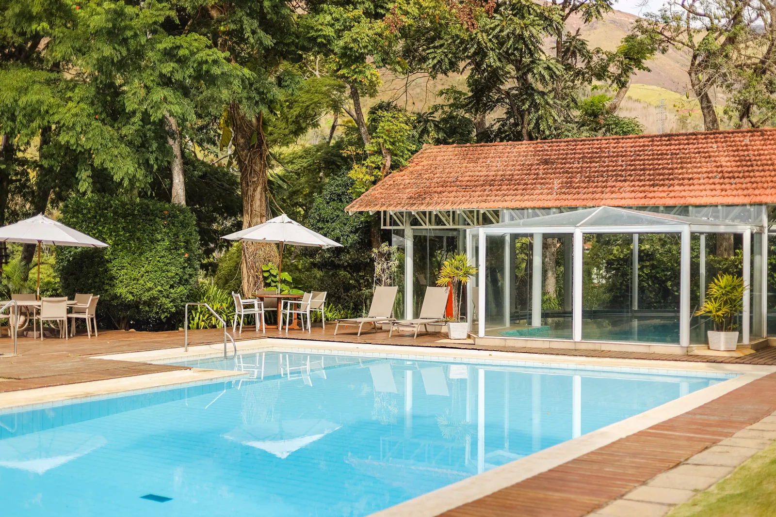 Piscina externa vista do gramado, com o salão envidraçado ao lado