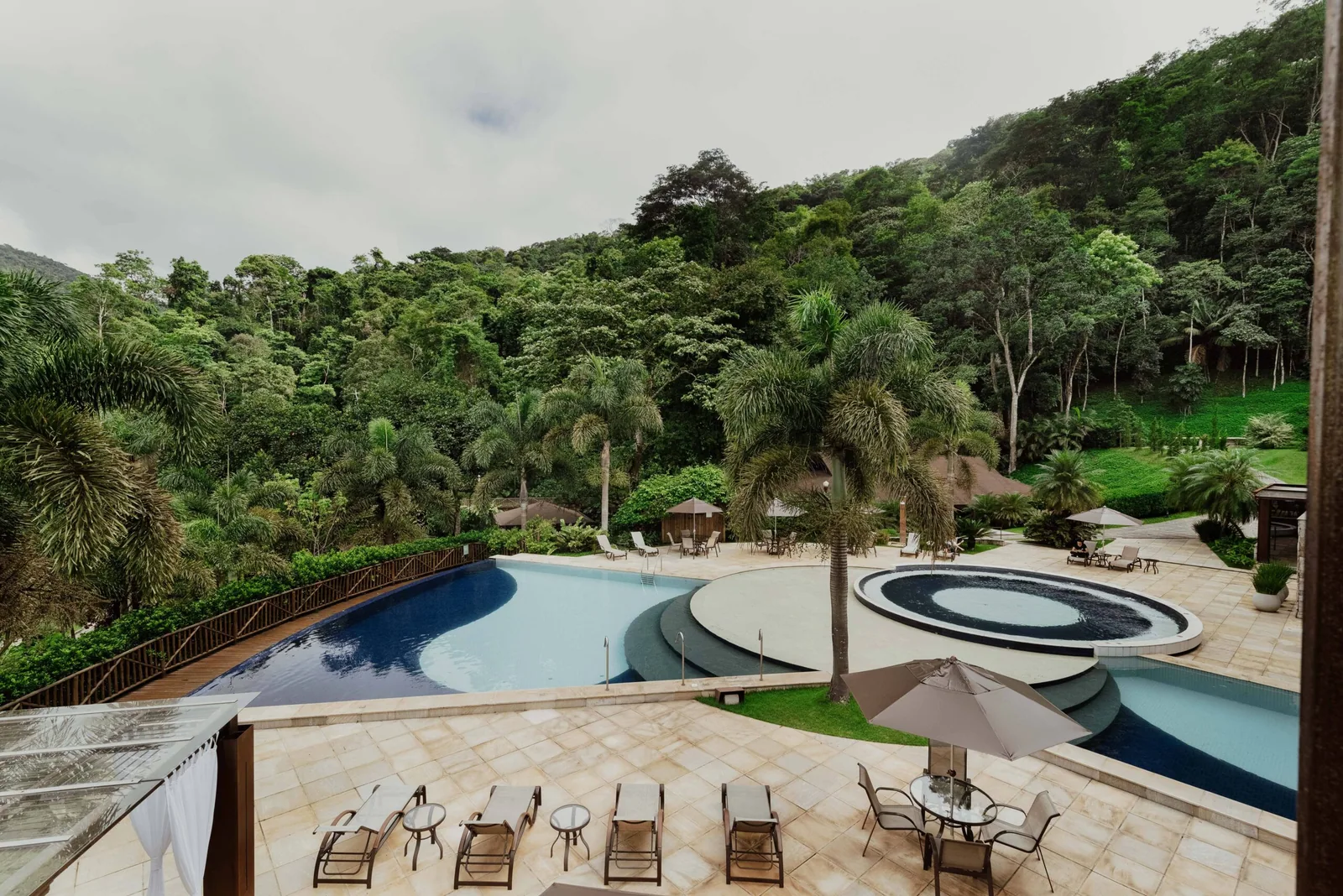 Vista geral das piscinas e do jardim do Rituaali, com a mata da Mantiqueira ao fundo