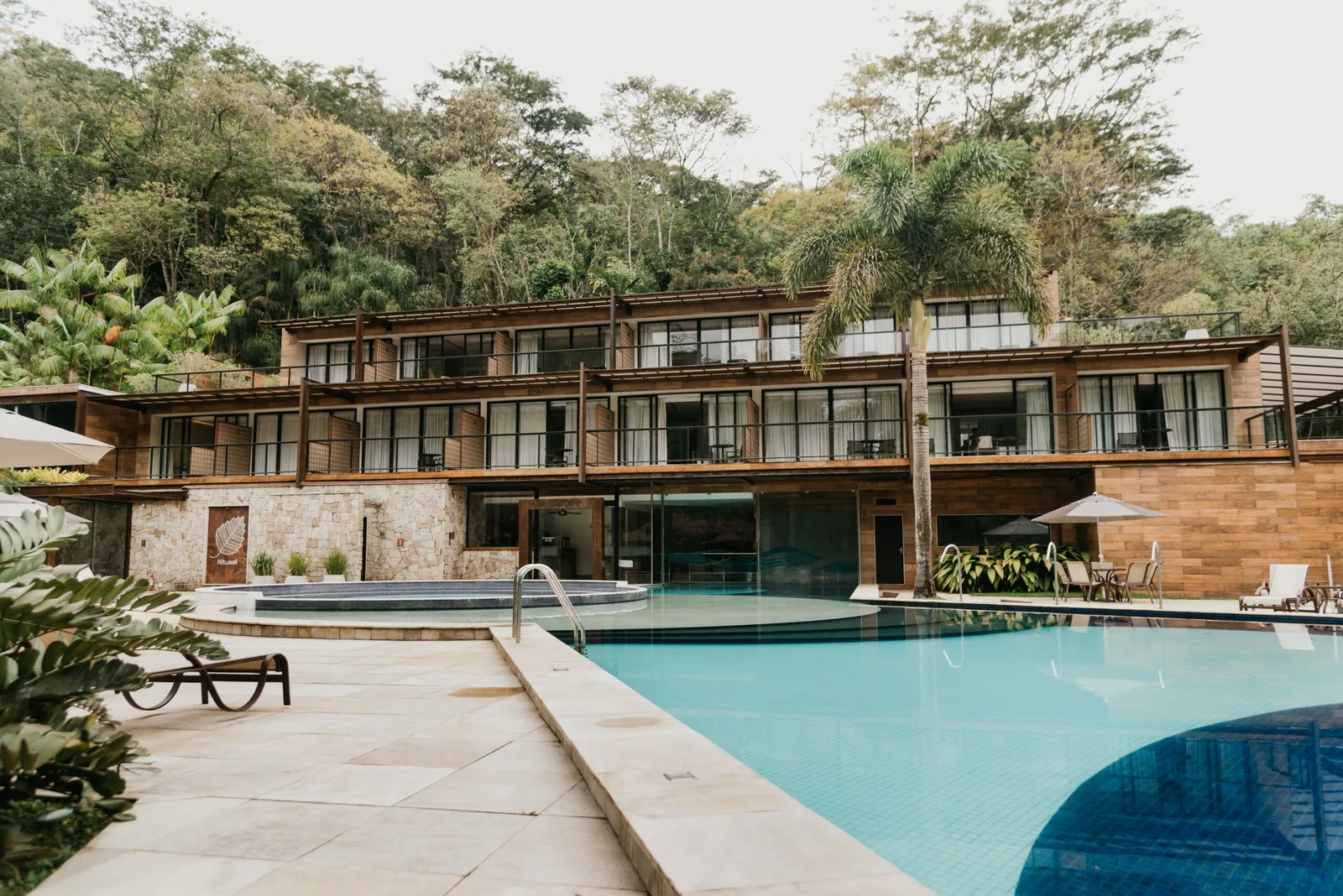 Prédio de apartamentos de madeira e vidro, de frente para a piscina