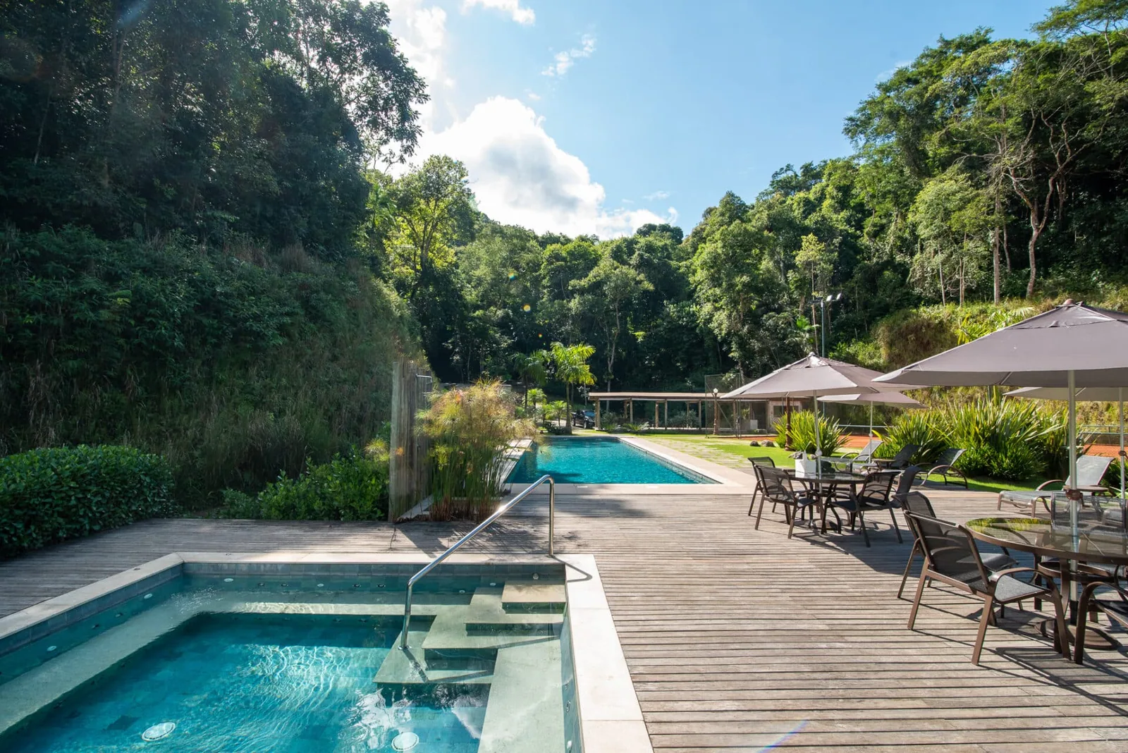 Piscina externa com deck de madeira e espreguiçadeiras