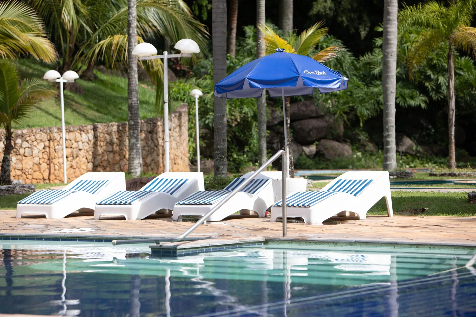 Piscina externa do Spa Med, com espreguiçadeiras e guarda-sol