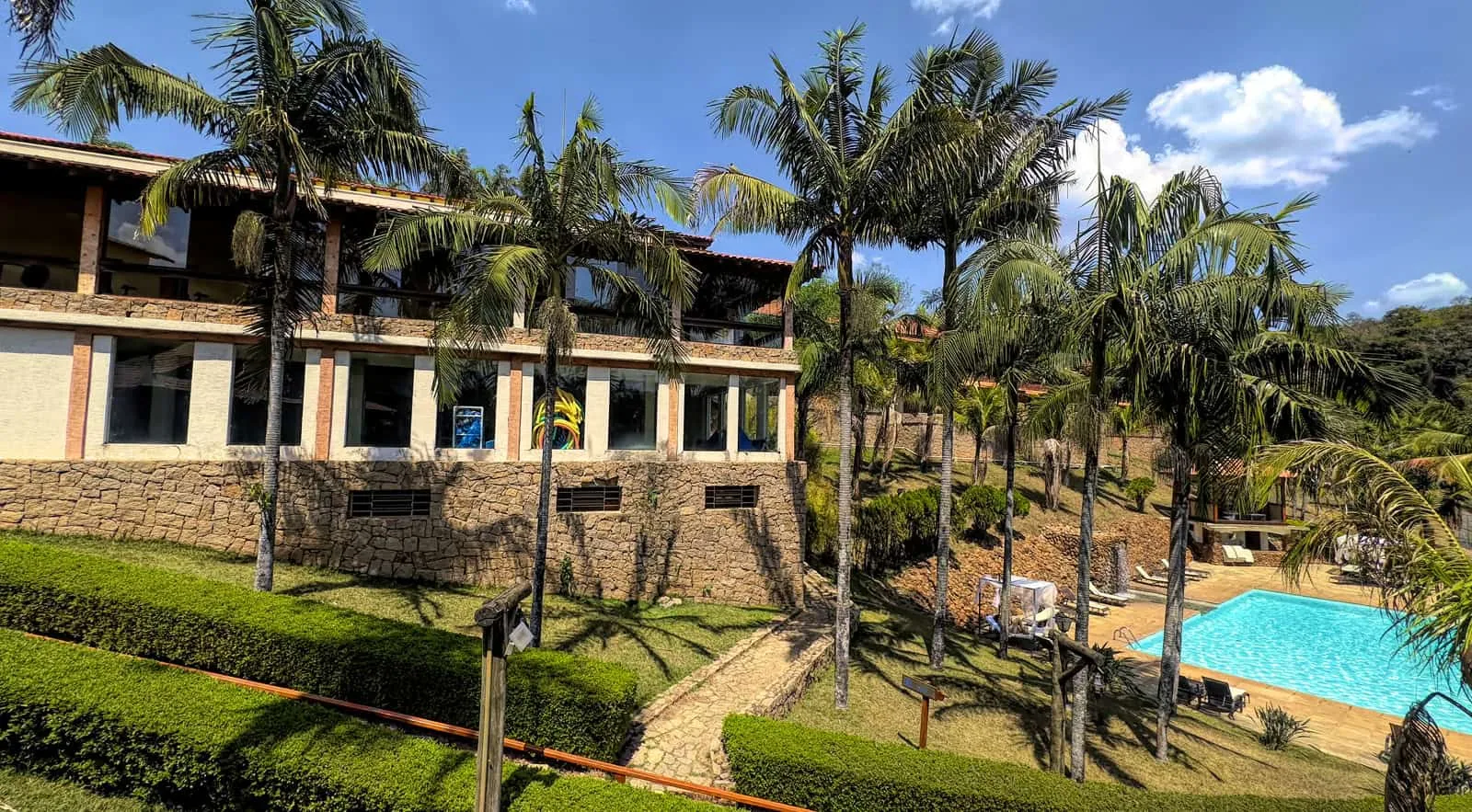 Prédio de apartamentos do SPA Recanto entre palmeiras, com a piscina externa abaixo